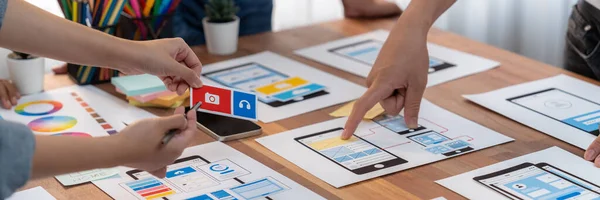 stock image Panorama shot of front-end developer team brainstorming UI and UX designs for mobile app on paper wireframe interface. User interface development team planning for user-friendly UI design. Scrutinize