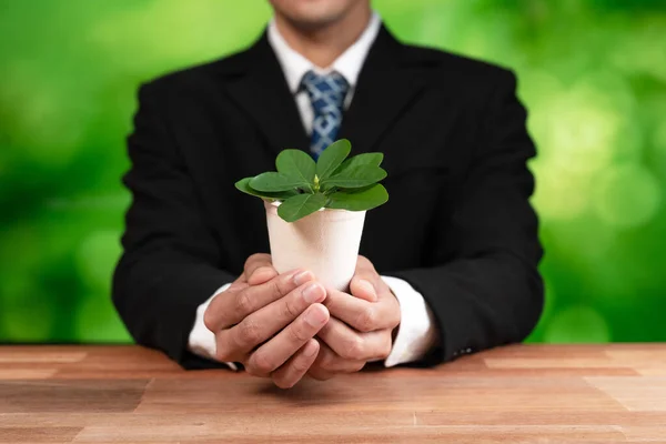 stock image Businessman holding plant pot with his hand promoting forest regeneration and natural awareness. Ethical green business with eco-friendly policy utilizing renewable energy to preserve ecology. Alter