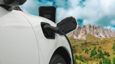 Temiz çevre için temiz enerjinin yol açtığı ilerici elektrikli araba kavramının arka planı olarak dağın tepesinde bulutun zaman kavramının yer aldığı doğal manzara. EV araba şarj istasyonunda şarj oluyor..