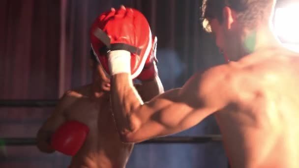 アジア人と白人ムエタイのボクサーは激しいボクシングトレーニングセッションでパンチを放つ スパーリングトレーナーにパンチストライキを提供し ムエタイのボクシング技術とスキルを紹介します インペトゥス — ストック動画