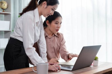 Modern ofis çalışma alanında iş birliği yapan iki genç ofis çalışanı, modern ofis çalışanı olarak profesyonelliklerini sergileyerek, dizüstü bilgisayarda tartışıyorlar ve birlikte çalışıyorlar. Coşkulu.