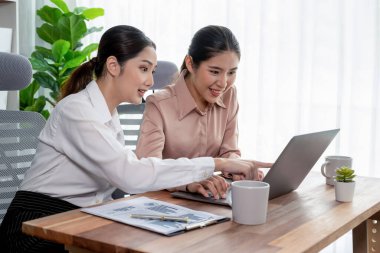 Modern ofis çalışma alanında iş birliği yapan iki genç ofis çalışanı, modern ofis çalışanı olarak profesyonelliklerini sergileyerek, dizüstü bilgisayarda tartışıyorlar ve birlikte çalışıyorlar. Coşkulu.