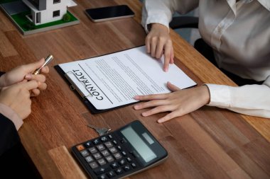 Temsilciyle ev kredisi sözleşmesini gözden geçiriyorum. Mali belgeleri ve vergi oranlarını, mülkiyet sahibi olmak için hesap makinesiyle analiz ediyorum. Yeni ev alımı ve finansman için anahtar imza. Coşkulu.