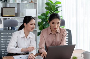 Modern ofis çalışma alanında iş birliği yapan iki genç ofis çalışanı, modern ofis çalışanı olarak profesyonelliklerini sergileyerek, dizüstü bilgisayarda tartışıyorlar ve birlikte çalışıyorlar. Coşkulu.