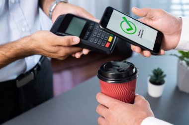 NFC QR kod cihazı ile el ele tutuşan akıllı telefon, hızlı dijital işlemler için temas kurulamayan ödeme kodlarını tarıyor. Modern yaşam tarzı ödeme teknolojisi için cep telefonundaki online bankacılık uygulaması. coşkulu