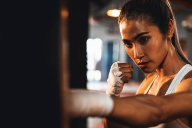 Asyalı kadın Muya Thai boksör eğitimi, spor salonunda kum torbasına yumruk atma. Sağlıklı spor ve spor yaşam tarzı, boks maçı için güç ve dayanıklılık eğitimi. Impetus