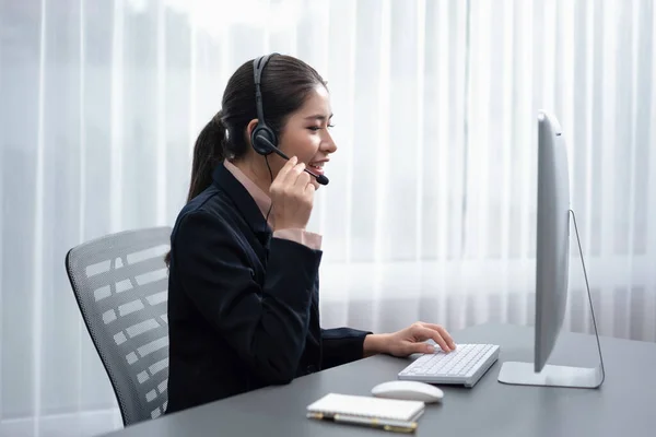 Asian call center with headset and microphone working on her laptop. Female operator provide exceptional customer service. Supportive call center agent helping customer on inquiry. Enthusiastic
