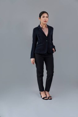 Kendine güvenen genç iş kadınının tüm vücut boyu resmi izole bir arka planda duruyor, resmi siyah takım elbise içinde poz veriyor. Ofisteki kadın ya da yönetici, zeki ve profesyonel görünümlü. Coşkulu.