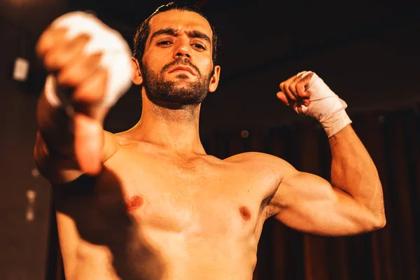 stock image Boxing fighter shirtless posing, caucasian boxer punch his bare fist and wrap in front of camera, aggressive stance and ready to fight at the boxing ring. Impetus