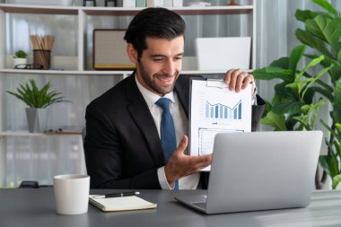 Siyah takım elbiseli profesyonel işadamı, online toplantı sırasında dizüstü bilgisayarla finansal veri ya da BI belgesi sunuyor. Etkili uzaktan çalışmanın sanal toplantı sunumuyla uzaktan çalışma konsepti. Coşkulu