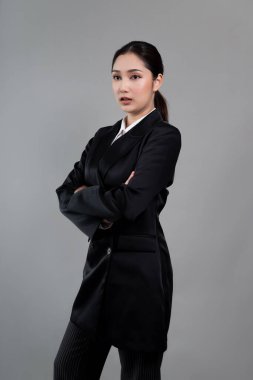 Kendine güvenen genç iş kadını, izole edilmiş bir arka planda duruyor, resmi siyah takım elbiseyle poz veriyor. Ofisteki kadın ya da yönetici, zeki ve profesyonel görünümlü. Coşkulu.