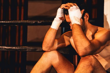 Yorgun ve yorgun Kafkasyalı boksör boks eldivenini çıkardı ve yoğun bir antrenman veya dövüş müsabakasından sonra ringin kenarında dinlenerek oturdu. Impetus