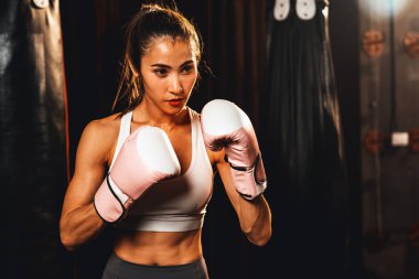 Kadın Muay Muay Tai boksörü savunma pozisyonu aldı. Spor salonunda eldiven giyiyordu. Poz vermeye, boks antrenmanına ve profesyonel dövüş sanatlarına hazırdı. Impetus