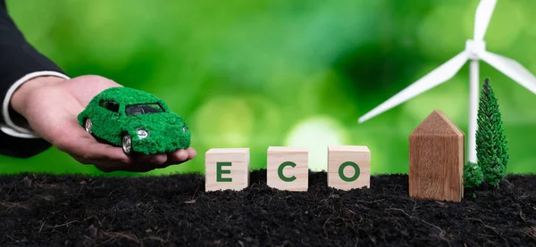商人手持绿色电动车 使用清洁可持续的发动机 在肥沃的土壤背景下的木制立方体上有生态符号 自然意识和绿色环境方面的二氧化碳零排放 改变了 — 图库照片