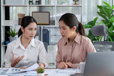 Modern ofis çalışma alanında iş birliği yapan iki genç ofis çalışanı, modern ofis çalışanı olarak profesyonelliklerini sergileyerek, dizüstü bilgisayarda tartışıyorlar ve birlikte çalışıyorlar. Coşkulu.