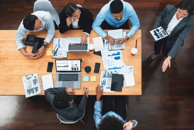 Modern toplantı odasındaki TV ekranında veri analizi paneliyle üst görünüm iş sunumu. İş adamlarının iş pazarlama stratejisini planlamak için beyin fırtınası yapması ya da birlikte çalışması. Uyum