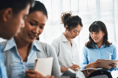 Gülümseyen Asyalı ofis çalışanı arkadaş canlısı ofis ortamında birlikte çalışıyor. İş yerinde, üretken bir ekip çalışması ve paylaşım fikri olan bir grup mutlu iş adamı. Çok titiz.