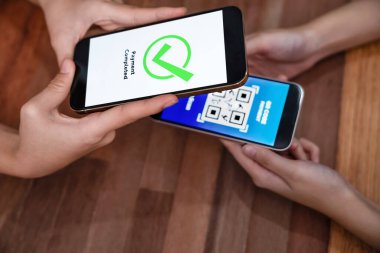 QR kodu parasız ödeme taraması için ekranda gösterilir. Kapalı eller, mobil uygulamadan elektronik işlem yoluyla para aktarmak için akıllı telefonu tutuyor. Hızlı ödeme için barkod teknolojisi. Coşkulu.