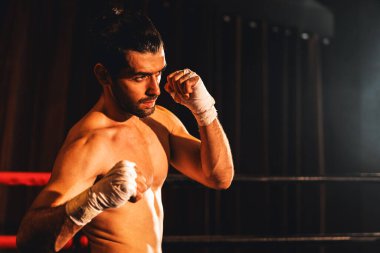 Üstsüz boksör pozu veren, beyaz boksör yumruğunu yumruklayıp kameranın önüne geçiyor, agresif duruşunu takınıyor ve boks ringinde dövüşmeye hazır. Impetus