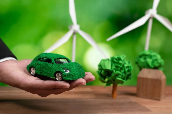在办公室里持绿色生态车模型的商人 环保型企业使用电动汽车进行环保型交通 公司对二氧化碳零排放负责 改变了 — 图库照片