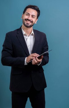 Resmi takım elbiseli kendine güvenen işadamı elinde tabletle sürpriz bir şekilde terfi ya da reklam arıyor. Yüz ifadeleri ve jestler, izole bir arkaplanda heyecan ve şaşkınlığa işaret ediyor. Coşkulu