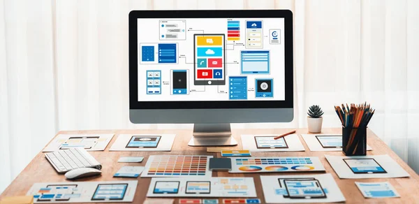 Stock image Digital and paper wireframe designs for web or mobile app UI UX display on laptop computer screen. Panoramic shot of developer workspace for brainstorming and design application framework. Scrutinize