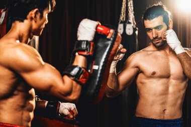 Asyalı ve Kafkasyalı Muay Thai boksörü boks antrenmanında boks antrenmanında boks antrenörüne yumruk atma, Muay Thai boks tekniği ve becerilerini sergileme. Impetus