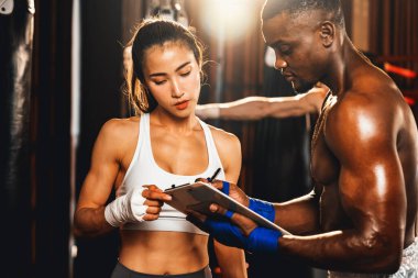 Asyalı bayan Muay Thai boksörü ve kişisel boks antrenörü spor salonundaki fiziksel ilerlemesini tartışıyor. Vücut kası gelişimine ve boks performansına bağlılığını yansıtıyor. Impetus