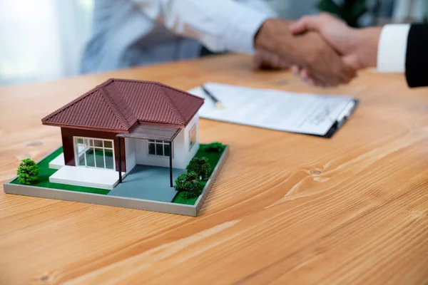 stock image Focus house sample or model with blur background of buyer handshaking with real estate agent. House loan contract with banker and client hand shake as symbol of successful agreement deal. Fervent