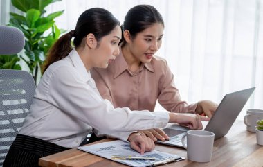 Modern ofis çalışma alanında iş birliği yapan iki genç ofis çalışanı, modern ofis çalışanı olarak profesyonelliklerini sergileyerek, dizüstü bilgisayarda tartışıyorlar ve birlikte çalışıyorlar. Coşkulu.