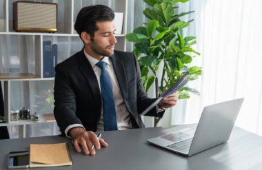 Modern ofis masasındaki modern profesyonel iş adamı çalışmak ve notlar yazmak için dizüstü bilgisayar kullanıyor. Ofisinde bilgisayar defteri üzerinde çalışan çalışkan bir ofis çalışanı. coşkulu