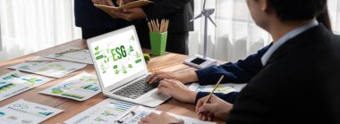 ESG 'nin çevresel sosyal yönetimi, çevre dostu şirket toplantılarında, temiz ve sürdürülebilir gelecekteki ekoloji için çevre korumasını uygulayan iş adamlarıyla dizüstü bilgisayarda sergileniyor. Önde.