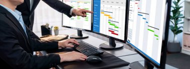 Projeyi koordine eden ve güncelleyen proje ekibi Gantt çizelge yazılımını kullanarak bilgisayarda program planladılar. Şirket işi için zaman ve süre belirleyen iş adamları. Önde.