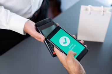 NFC QR kod cihazı ile el ele tutuşan akıllı telefon, hızlı dijital işlemler için temas kurulamayan ödeme kodlarını tarıyor. Modern yaşam tarzı ödeme teknolojisi için cep telefonundaki online bankacılık uygulaması. coşkulu