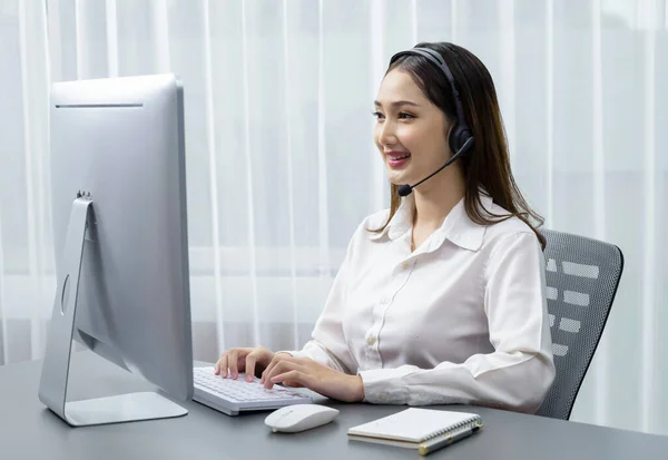Asian call center with headset and microphone working on her laptop. Female operator provide exceptional customer service. Supportive call center agent helping customer on inquiry. Enthusiastic