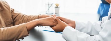 Doktor, doktor kliniğinde destekleyici ve profesyonel olduğu için genç hasta elini tutarken tıbbi teşhis raporunu ve şefkatli bir sağlık hizmeti danışmanlığı sunduğunu göster. Neoterik