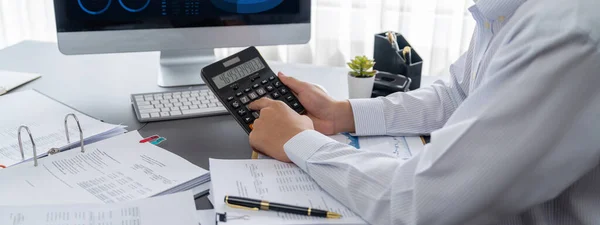 監査役は事務机の上で計算機で予算を計算する 会計事務所の専任会計士の専門家が財務書類を分析して収入を予測する — ストック写真