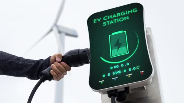 人工将电动车充电器从自然的电动车充电站拉出来 减少风力涡轮机场的二氧化碳排放 替代能源可持续性和电动汽车的技术进步 仔细阅读 — 图库视频影像