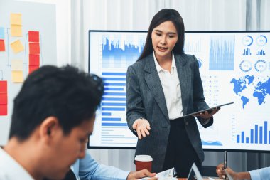 Genç Asyalı iş kadını modern toplantıda TV ekranında veri analizi paneli sunuyor. Bir grup iş adamıyla konferans odasında iş sunumu. Uyum