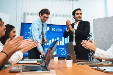 Kutlama jesti ve başarılı takım çalışması yapan bir grup mutlu çoklu etnik iş adamı başarılı satışlar yaptıktan sonra veya toplantı odasında ekranda pozitif finansal veri gösterimi yaptıktan sonra. Habiliment