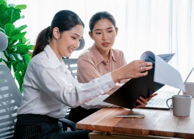 Modern ofis çalışma alanında iş birliği yapan iki genç ofis çalışanı, modern ofis çalışanı olarak profesyonelliklerini sergileyerek, dizüstü bilgisayarda tartışıyorlar ve birlikte çalışıyorlar. Coşkulu.