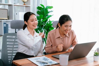 Modern ofis çalışma alanında iş birliği yapan iki genç ofis çalışanı, modern ofis çalışanı olarak profesyonelliklerini sergileyerek, dizüstü bilgisayarda tartışıyorlar ve birlikte çalışıyorlar. Coşkulu.