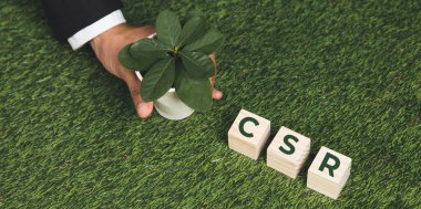 Üst düzey bir işadamı elinde CSR 'ı sembolize eden küplü bir saksı tutuyor. Karbondioksit salınımı politikası olmayan etik ve çevre dostu yeşil iş. Yeşil toplumdan sorumlu kurumsal bir sosyal sorumluluk üstlenin. Değiştir