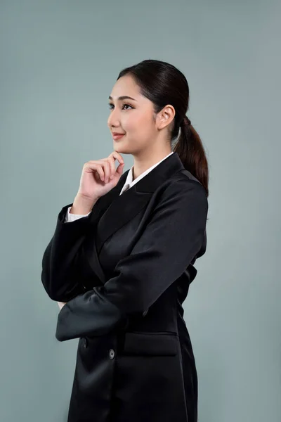 Stock image Confident young businesswoman stands on isolated background, posing in formal black suit. Office lady or manager with smart and professional appearance. Enthusiastic