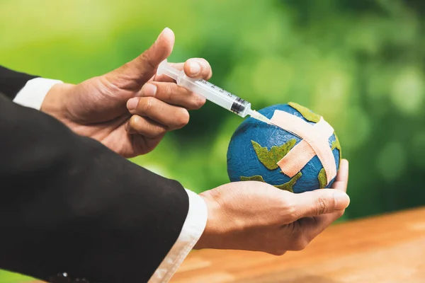 Businessman holds and inject medicine to paper earth as symbol of eco environmental awareness and healing planet earth for sustainable world with healthy ecology. Alter