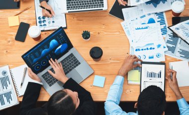 Panorama üst görüşlü çok ırklı analist ekibi, stratejik karar için finansal verileri analiz etmek amacıyla dizüstü bilgisayarda BI gösterge panelini kullanıyor. Fintech pazarlama göstergelerini analiz ediyor. Uyum