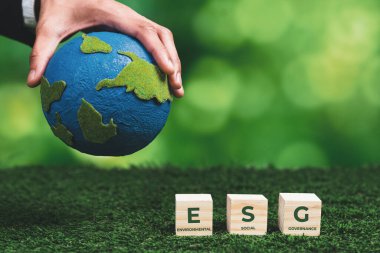 ESG sembolü ahşap küplü kağıt gezegen tutan bir iş adamı. Çevresel, sosyal ve yönetimsel dünyayı kurtarmak için sürdürülebilir şirket gelişimi. Değiştir