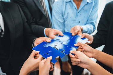Çok ırklı iş adamları yapboz parçalarını tutuyor ve onları etkili çözüm çözümleri olarak birleştiriyor takım çalışması, ortak görüş ve çeşitli yetenekleri birleştiren ortak hedef. Çok titiz.
