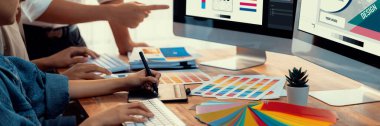 Grafik tasarımcısı, modern dijital stüdyo işyerinde profesyonel grafik ekibiyle benzersiz bir tasarım yaparken bilgisayar dizüstü bilgisayar ve grafik çizim kalemi üzerinde çalışır. Panorama çekimi. İnceleyin