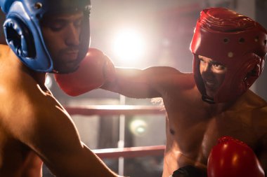 Kasklı iki atletik ve kaslı vücut boksörü ya da boks baş muhafızı vahşi bir boks maçında karşı karşıya. Boks dövüşçüsü boks ringinde dövüşüyor. Impetus